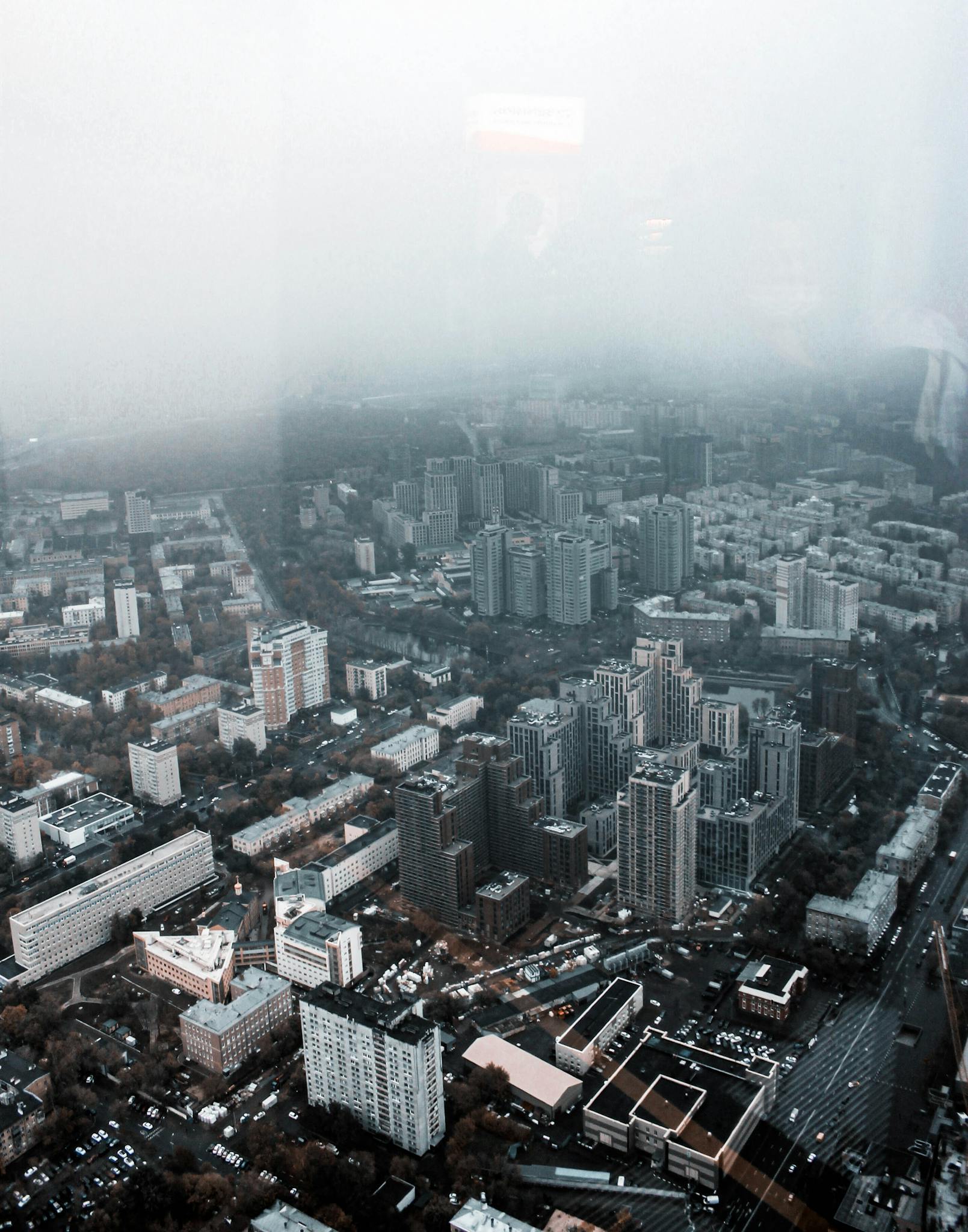 High-angle aerial view of a foggy urban cityscape, showcasing dense buildings and muted colors.